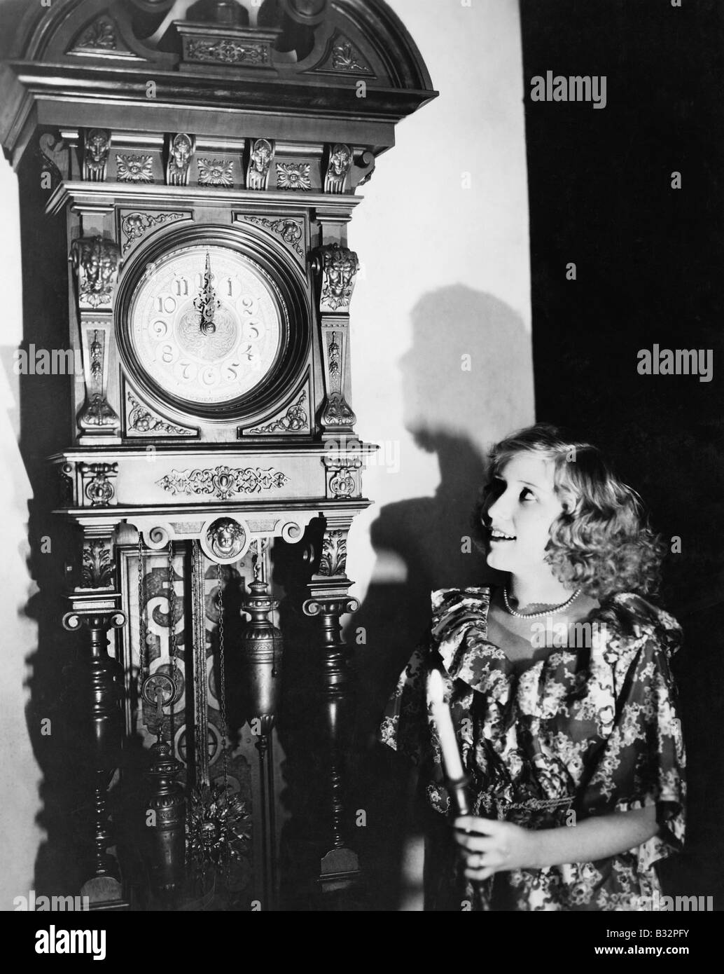 Woman with grandfather clock at midnight Stock Photo