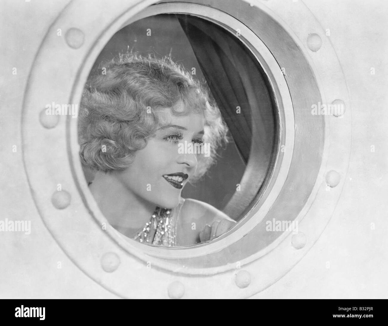 Woman looking through porthole Stock Photo