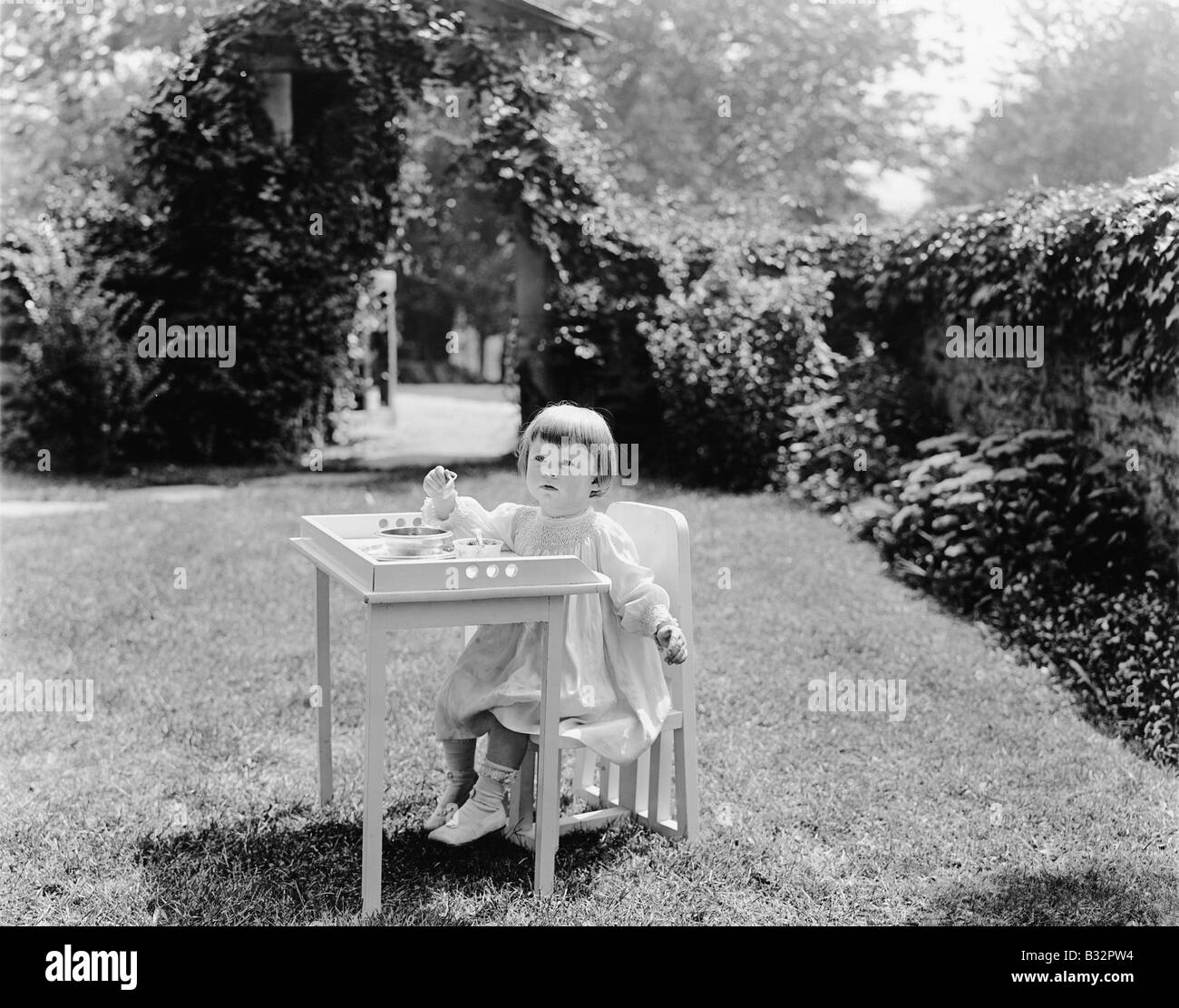 Toddler eating at table in garden Stock Photo