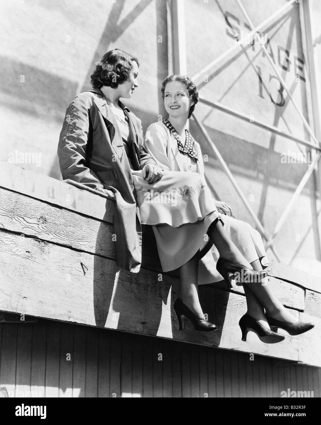 Two women sitting together on scaffolding Stock Photo