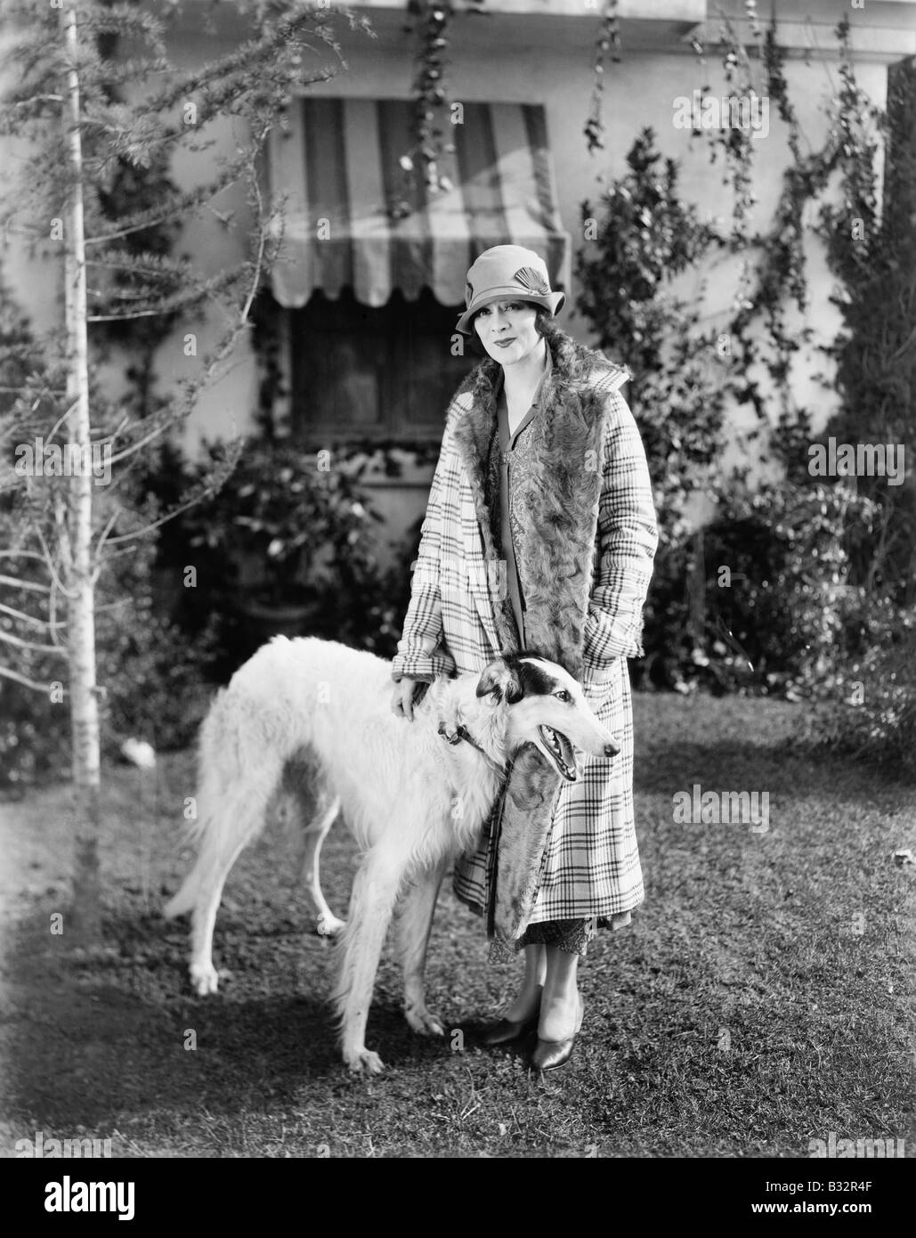 Young woman in coat and hat standing outside with her Russian Wolfhound Stock Photo