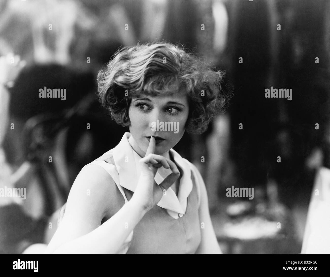 Woman holding finger in front her mouth signaling to be quiet Stock Photo