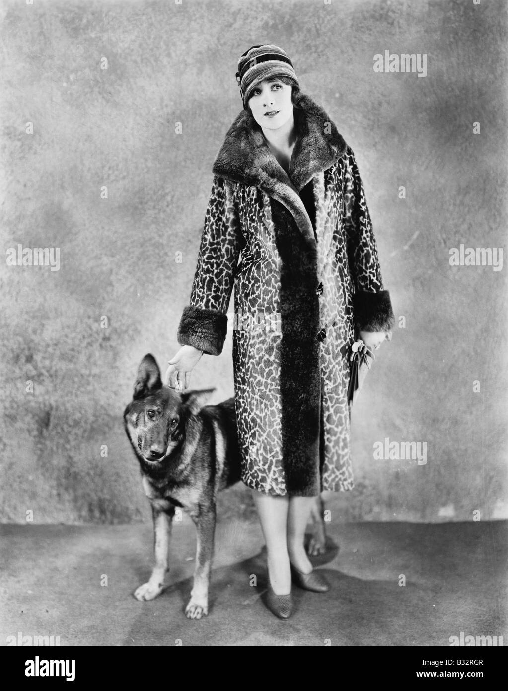 Woman in her Giraffe patterned fur coat her dog Stock Photo