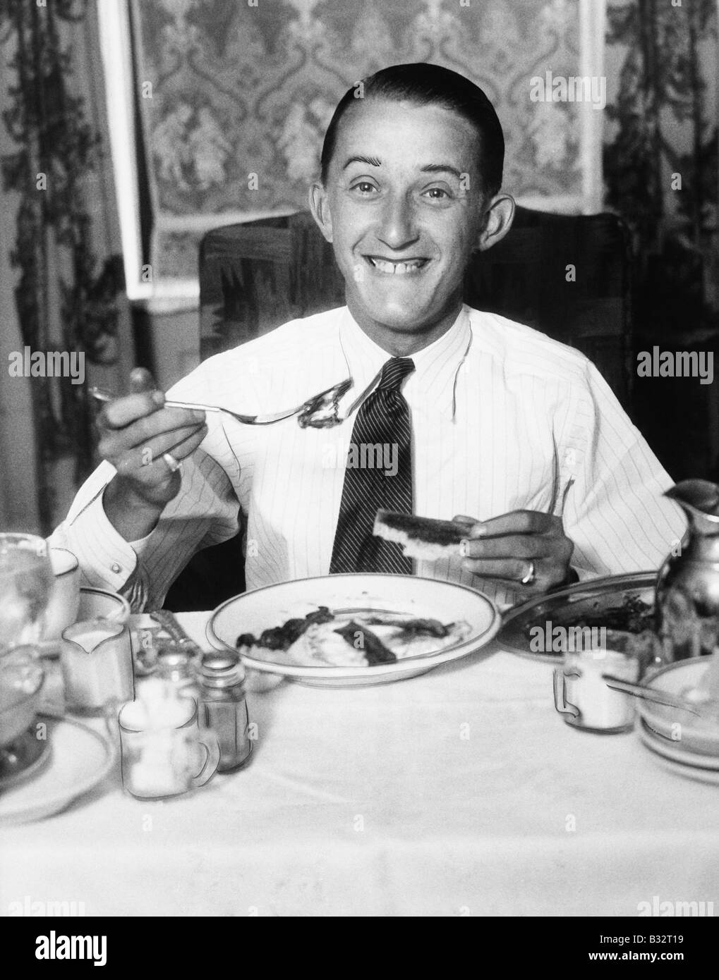 Young man having breakfast and smiling Stock Photo