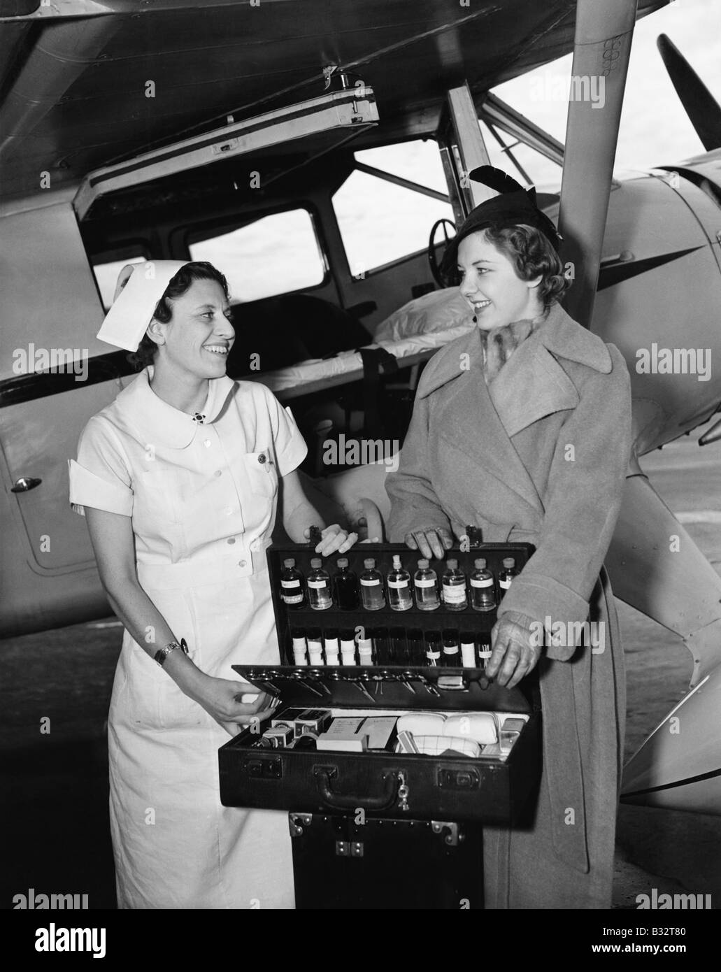 Female nurse with a young woman standing in front of an airplane and opening a medicine box Stock Photo