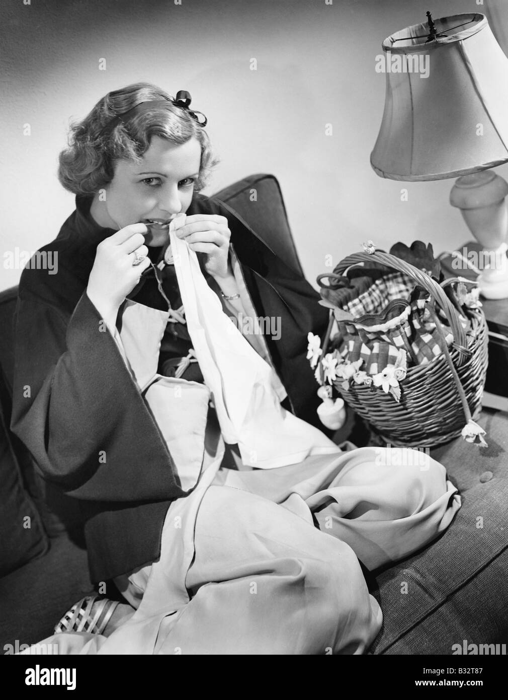 Portrait of a young woman cutting thread with her teeth Stock Photo Alamy