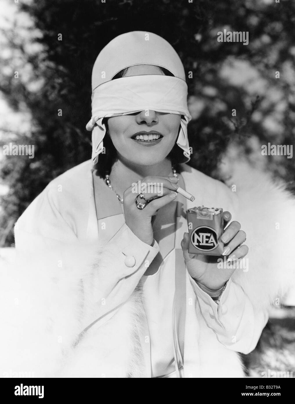 Young woman with blindfolded eyes taking out a cigarette from a cigarette  pack Stock Photo