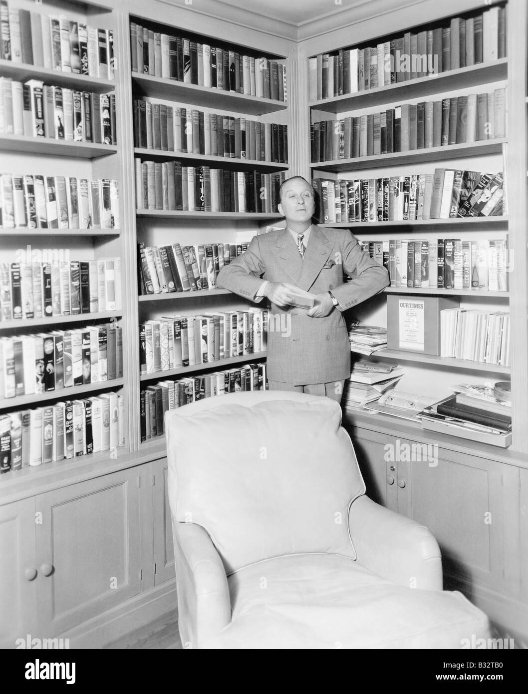 Man leaning against bookshelf library hires stock photography and