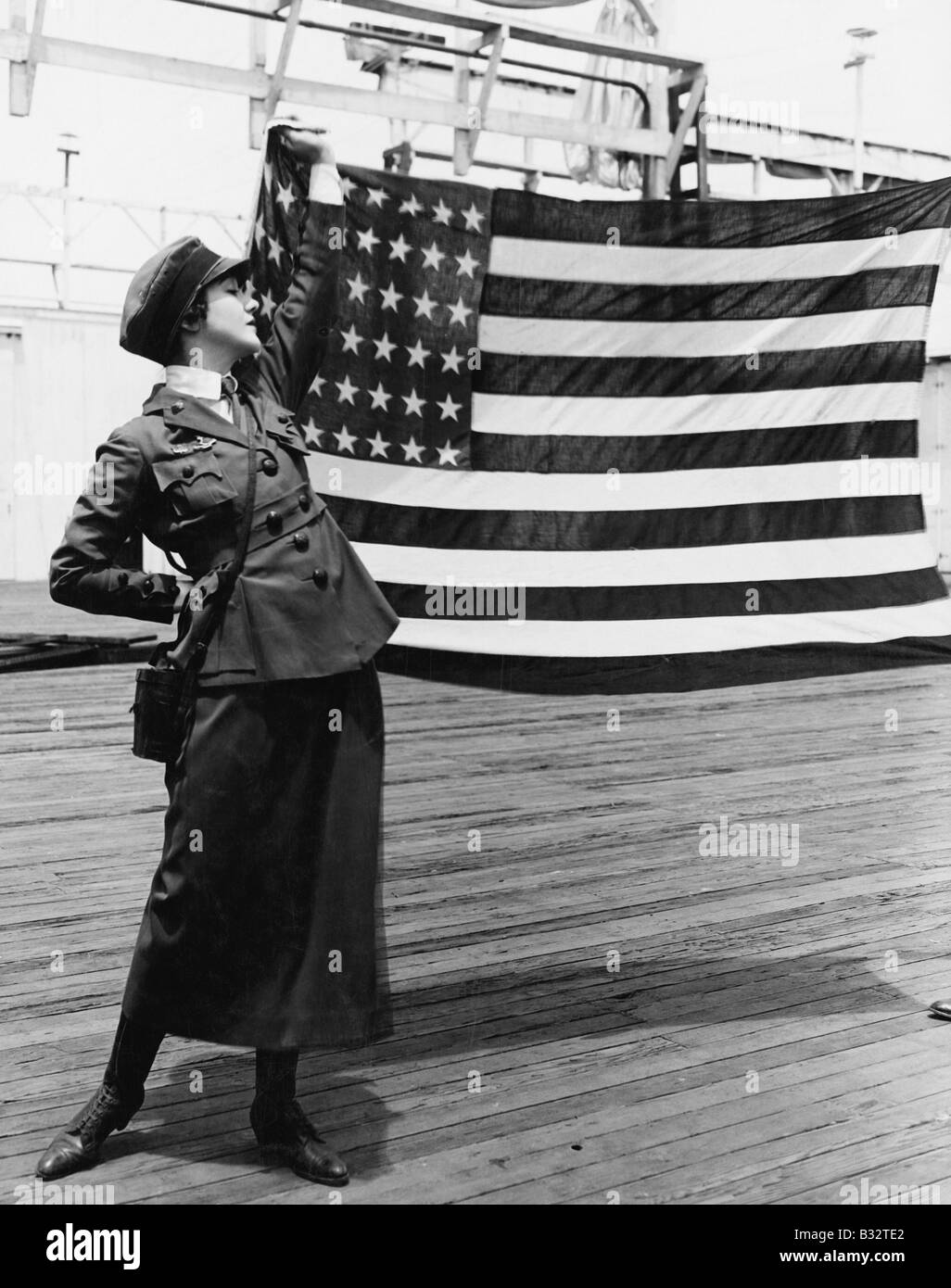 Young woman in military uniform holding up American flag Stock Photo