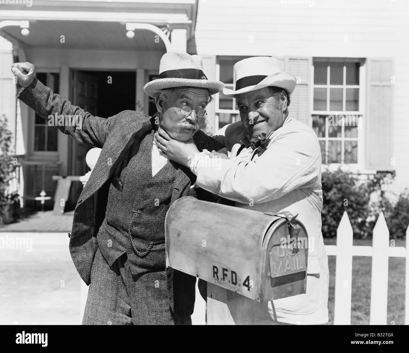 Two mature men fighting near a mail box in front of a house Stock Photo