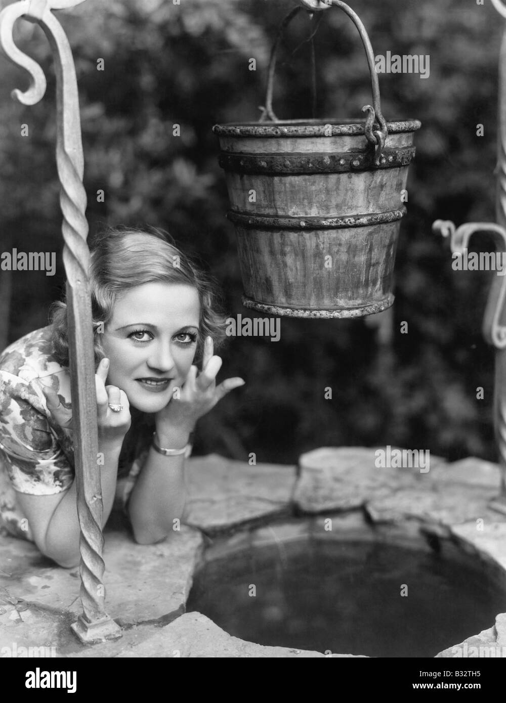Portrait of a woman leaning on a well with her finger crossed Stock Photo
