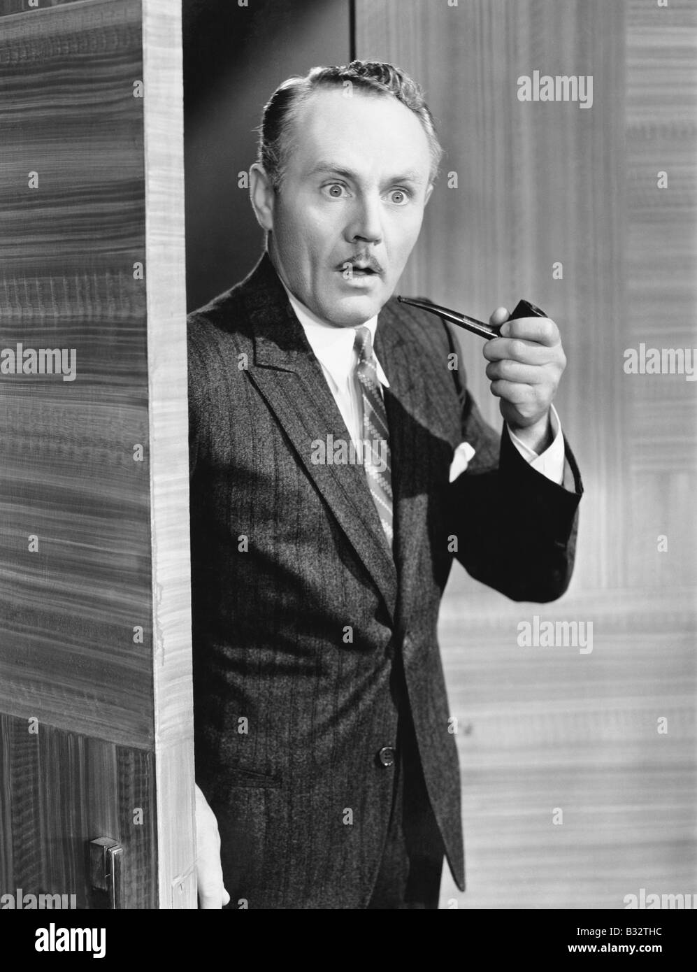 Man holding a pipe and standing at a doorway looking very surprised Stock Photo