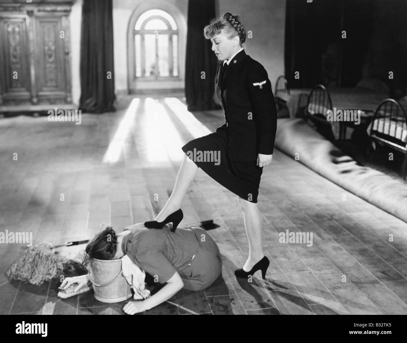 Female officer punishing her maid by forcing her head into a bucket Stock Photo