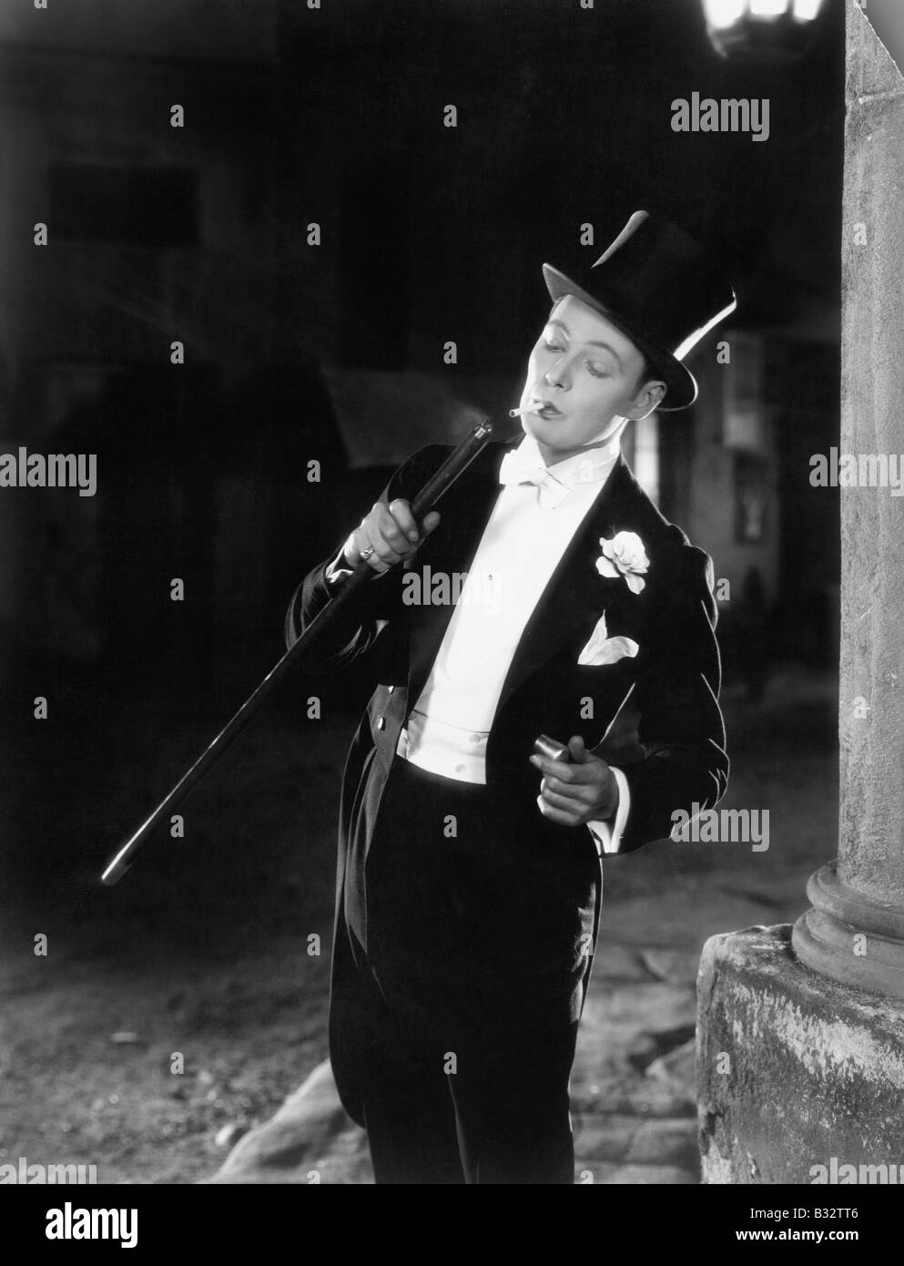 Young man in formal clothing lighting his cigarette with his walking stick Stock Photo