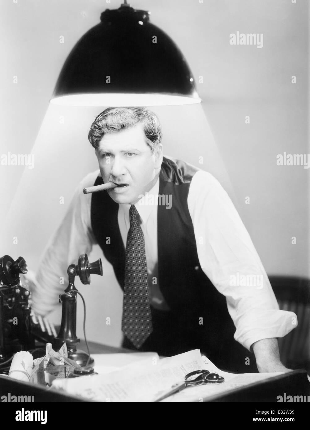 Man leaning over desk with ceiling light shining on him Stock Photo