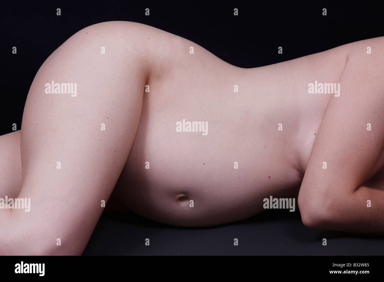 A pregnant woman is lying on her side, with her pregnant belly exposed. The  image is showing her hips and belly only Stock Photo - Alamy