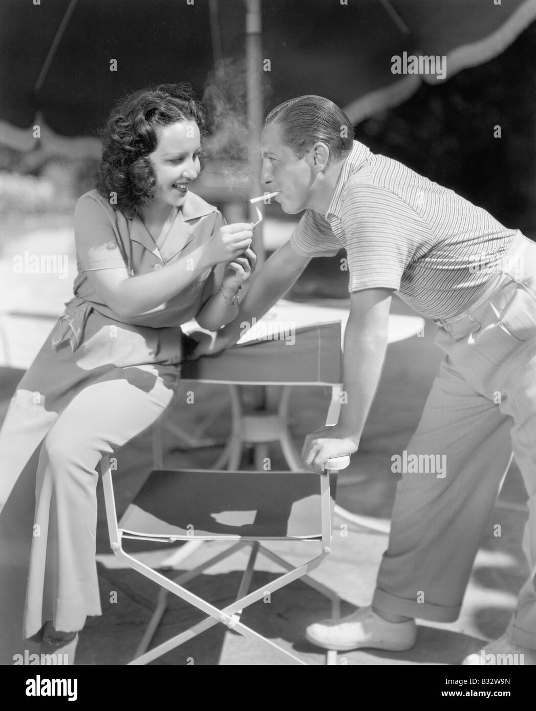 Woman giving a man a light for his cigarette Stock Photo