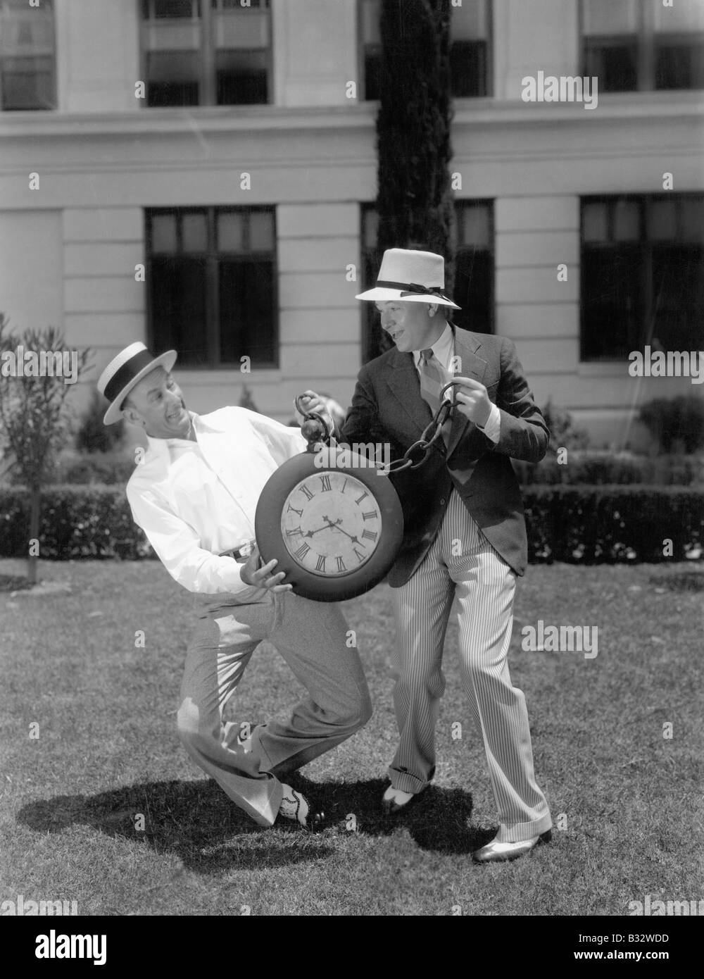 Two men wrestling with an oversized pocket watch Stock Photo