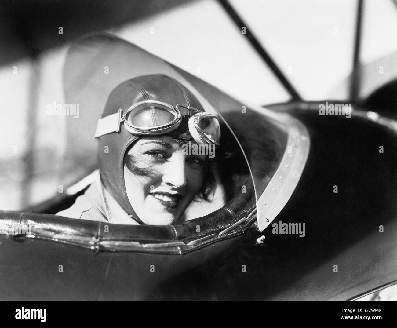 Young woman sitting in a biplane with hat and gargles Stock Photo