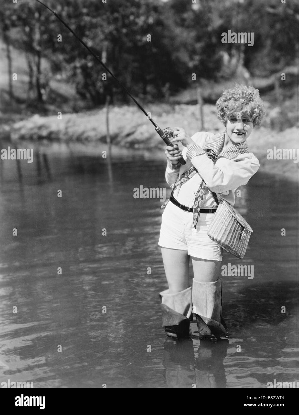 Young woman wearing waders holding a fishing rod Stock Photo