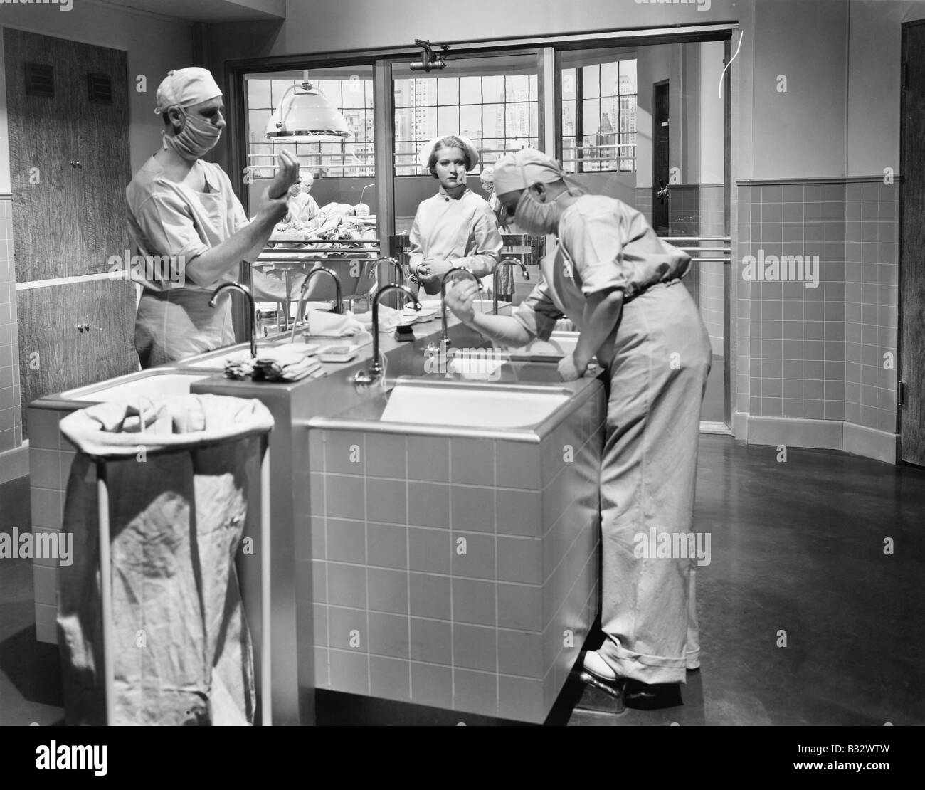 Two surgeons and a nurse in the scrub room preparing for an operation Stock Photo