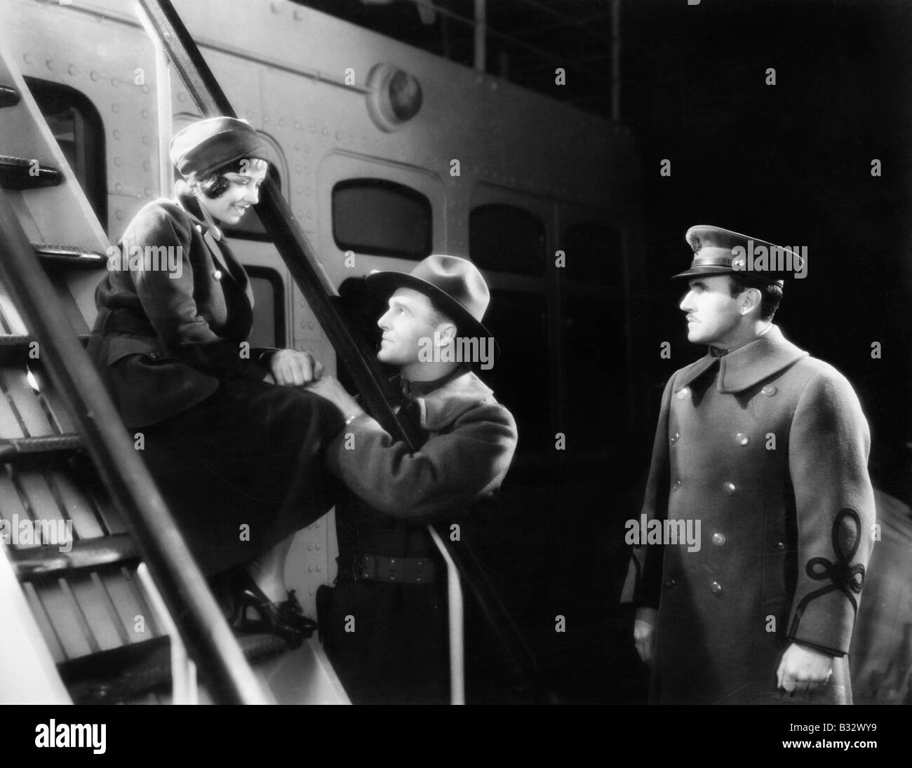 Two men talking to a young woman sitting on the ship's step Stock Photo