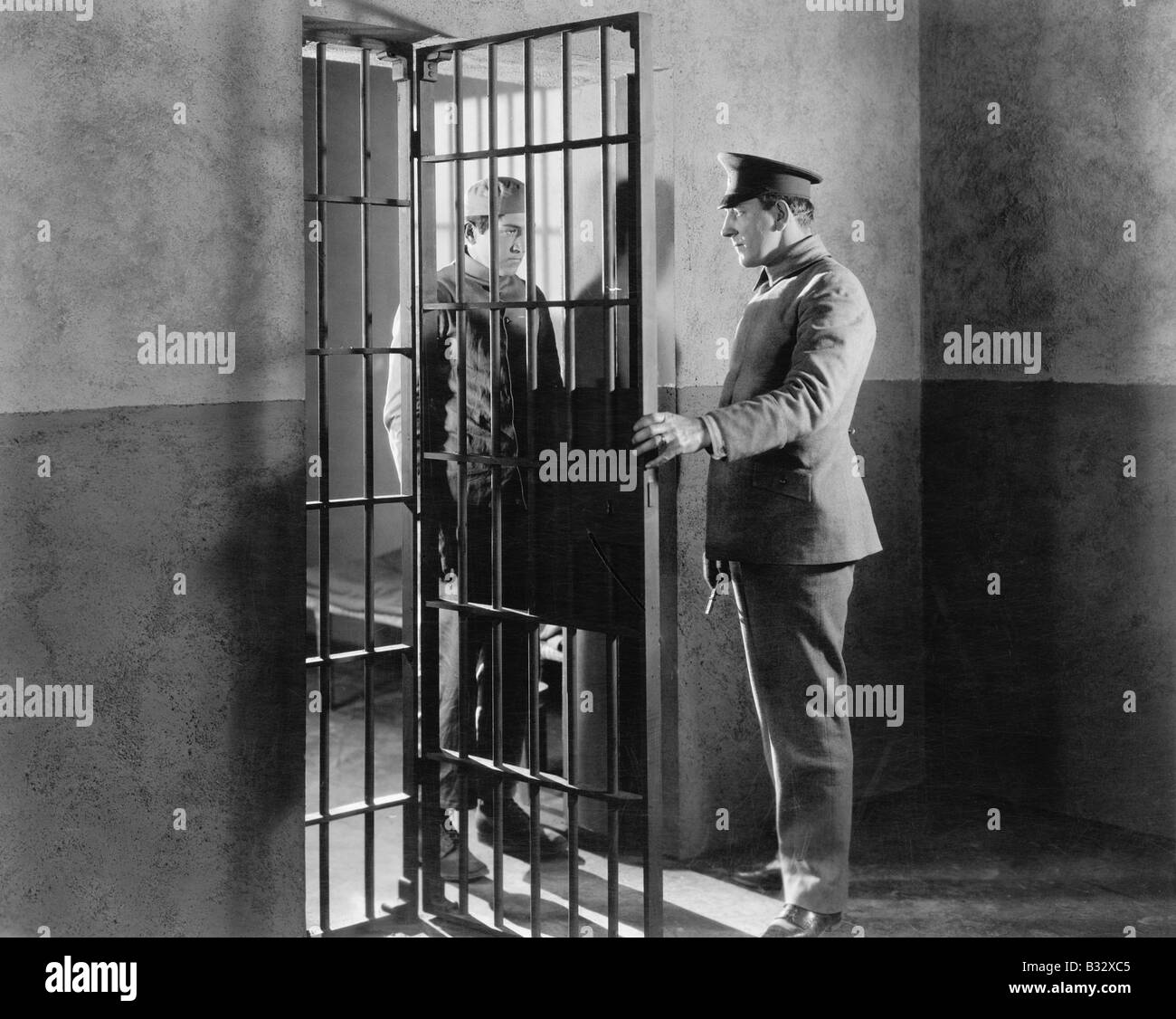 Policeman and prisoner in a jail cell Stock Photo