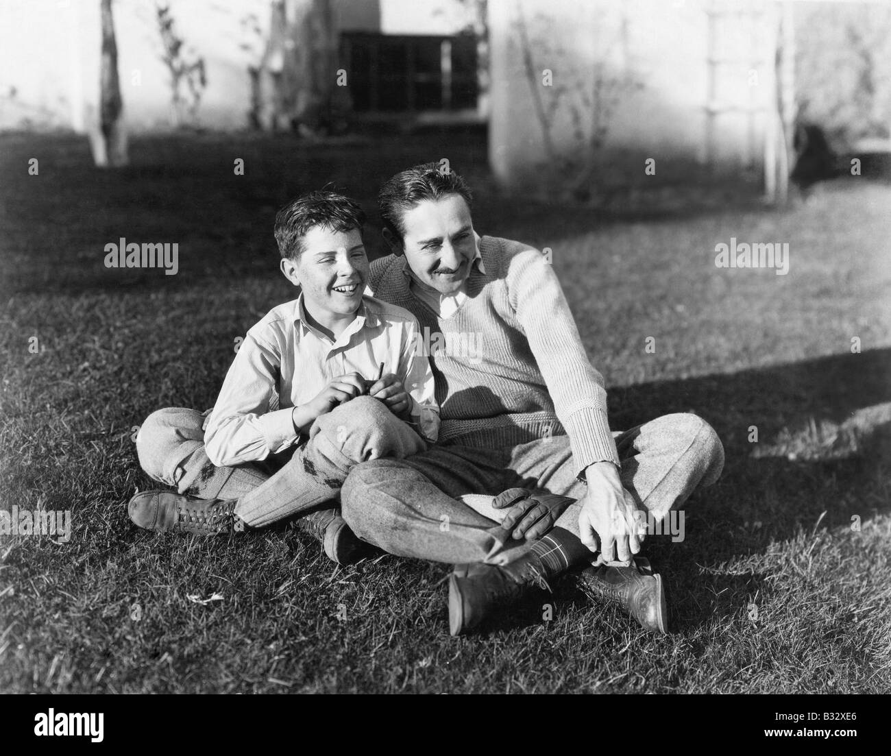 Father and son sitting together on the grass in the back yard Stock Photo