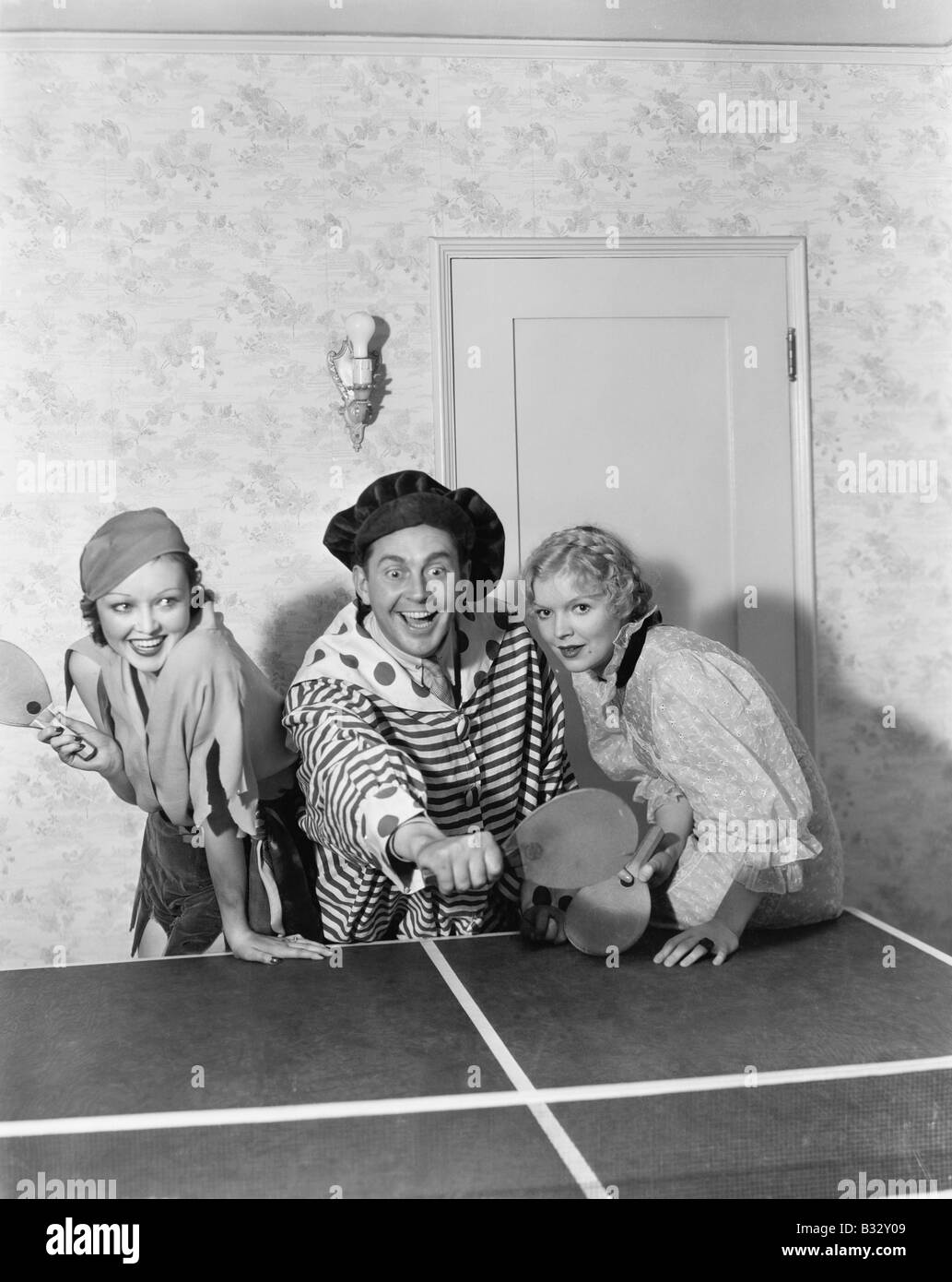 Two women and one man in a costume playing table tennis Stock Photo