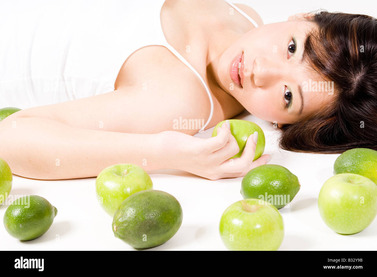 A beautiful young asian woman in white with apples and limes Stock Photo