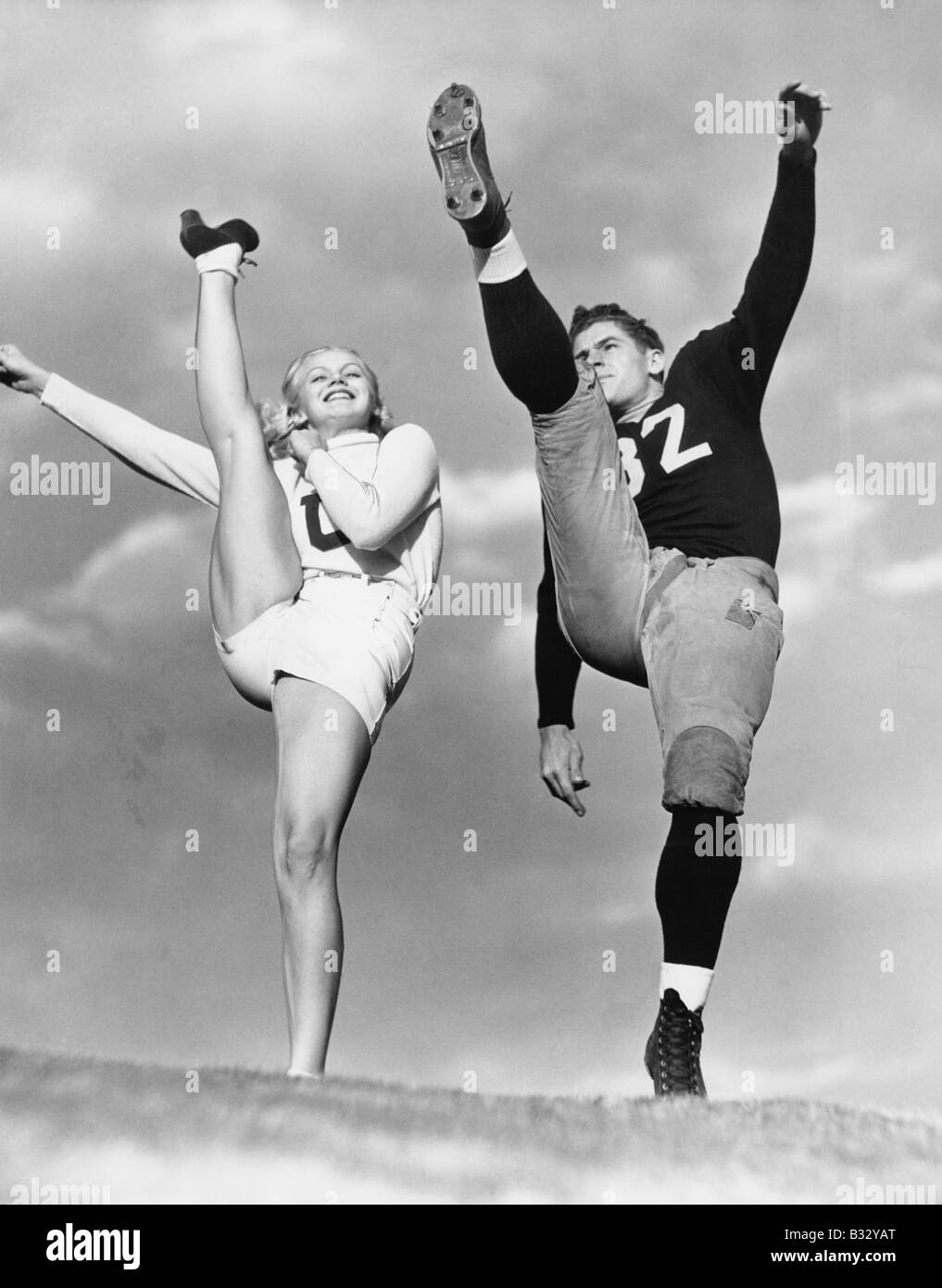 Cheerleader and football player kicking into the air Stock Photo