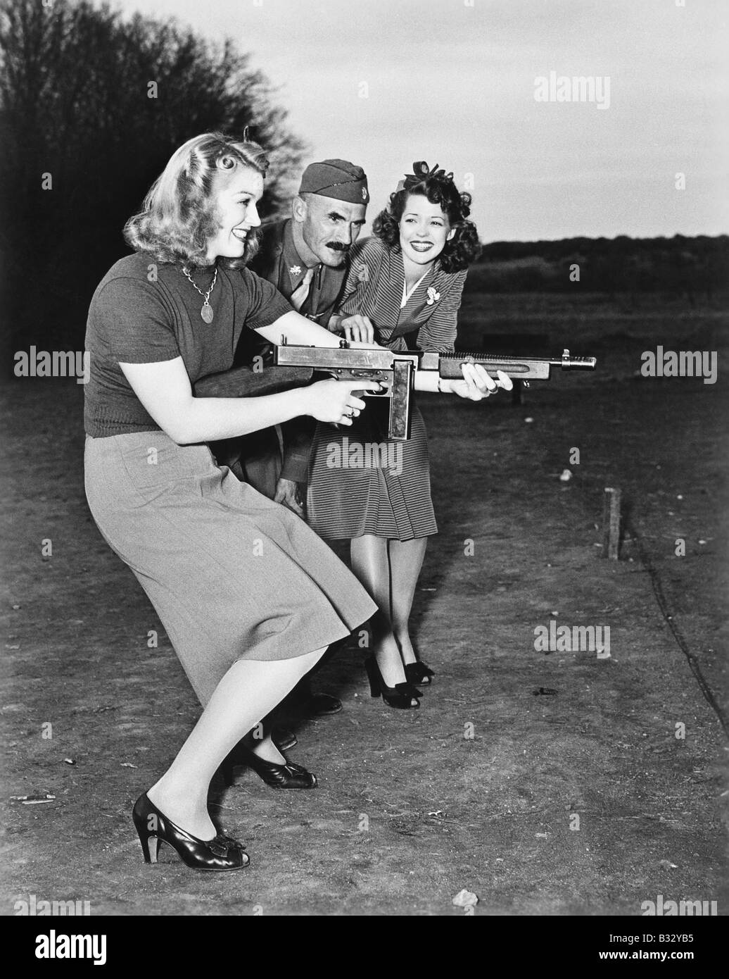 Two young women and a soldier trying out a machine gun Stock Photo
