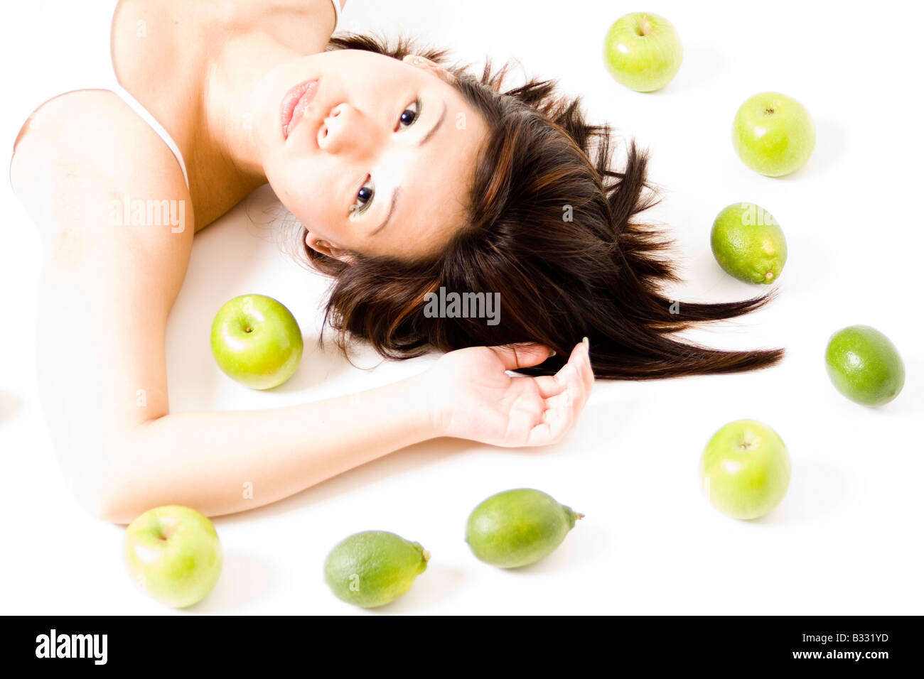A pretty young asian woman poses with green apples and limes Stock Photo