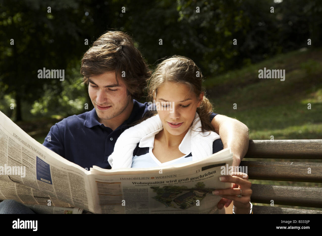 young couple sitting on a park bench with a map Stock Photo - Alamy