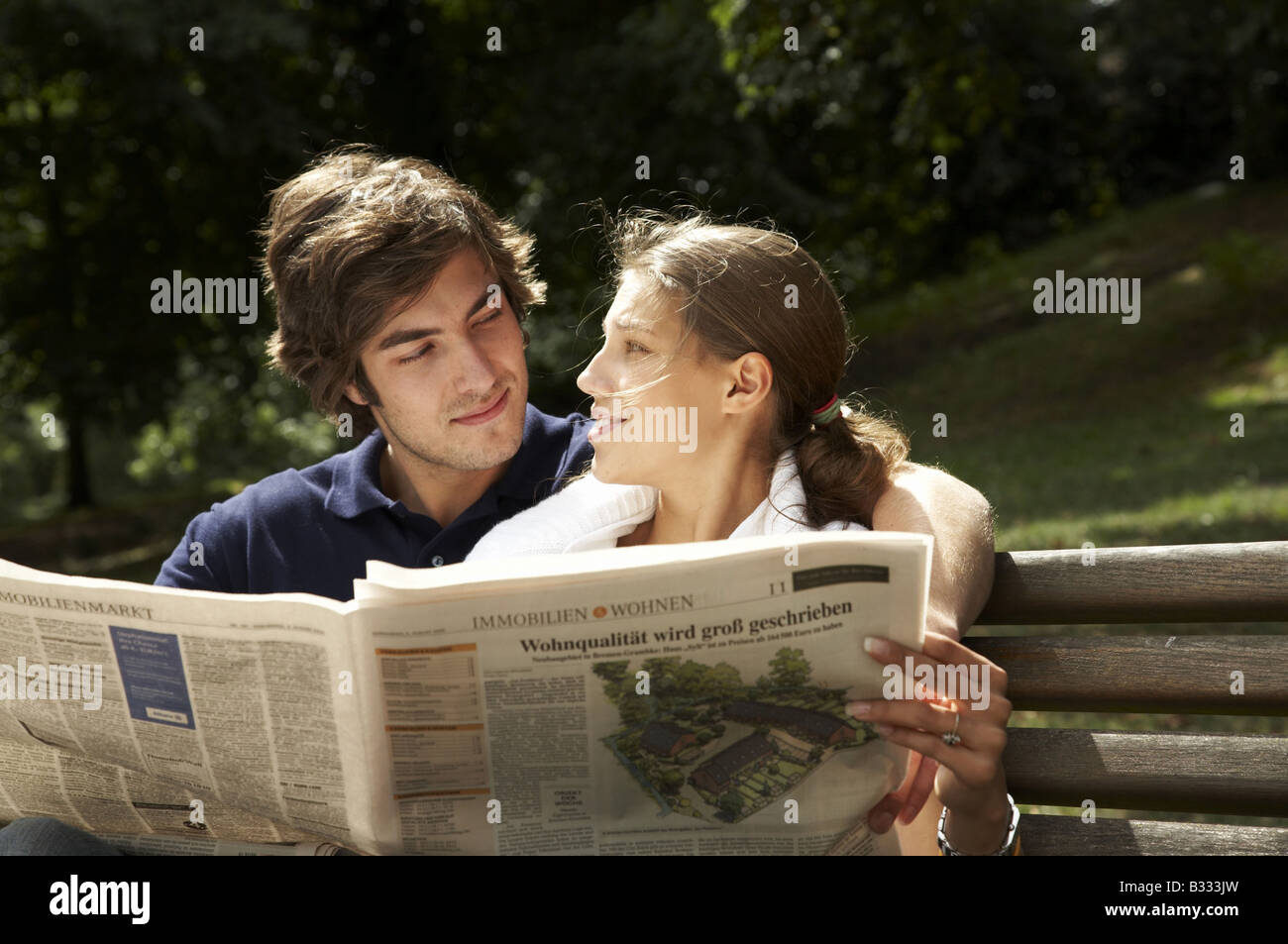 young couple sitting on a park bench with a map Stock Photo - Alamy