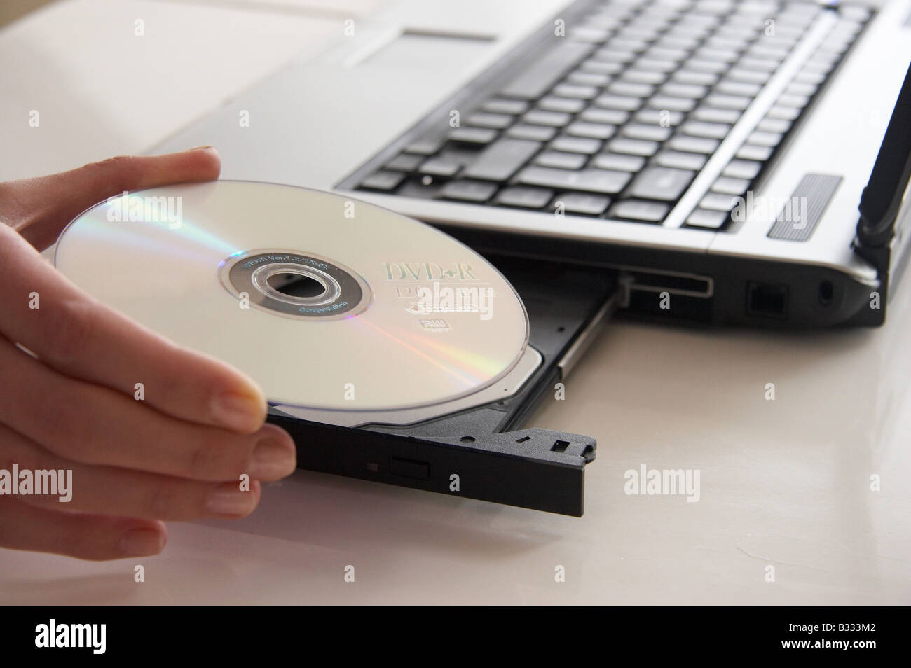 a hand putting a disc into a laptop Stock Photo - Alamy