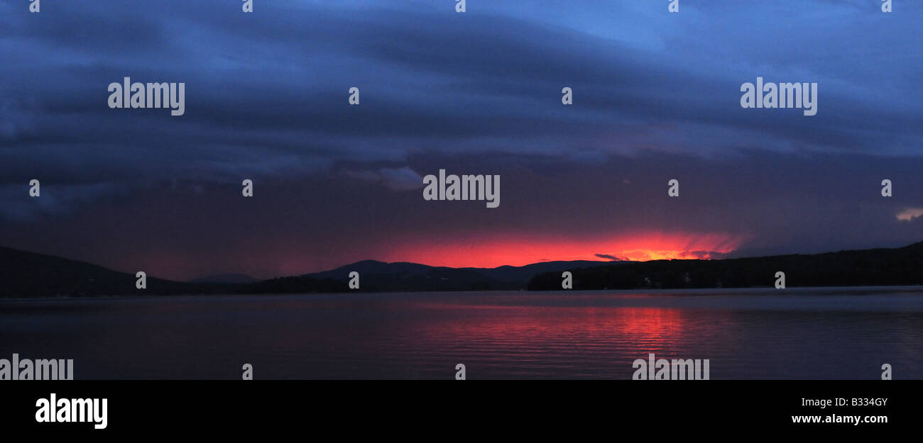 A panoramic view of the most spectacular sunset on a lake in Quebec, Canada’s Laurentian mountains, as two storefronts collide. Stock Photo