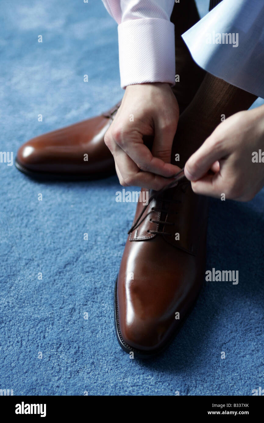 Businessman tying his shoe laces as he gets ready for work. Stock Photo