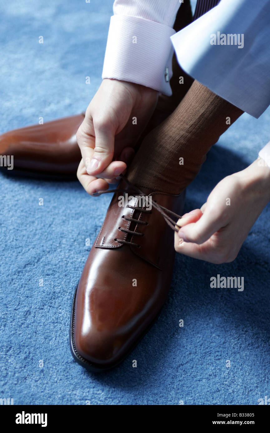 Businessman tying his shoe laces as he gets ready for work. Stock Photo