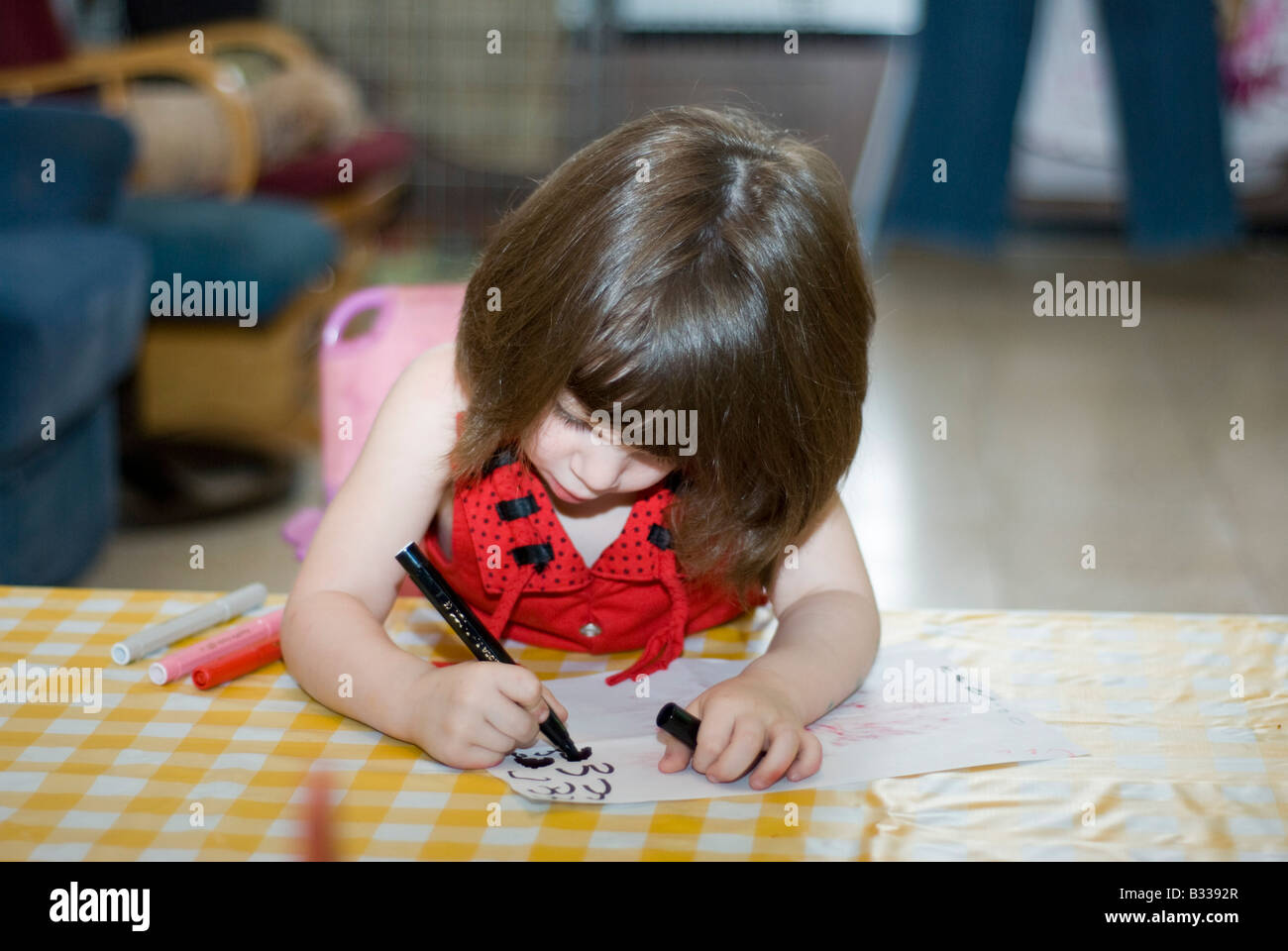 girl aged 3 drawing on paper with crayons Model Release Avalable Stock Photo