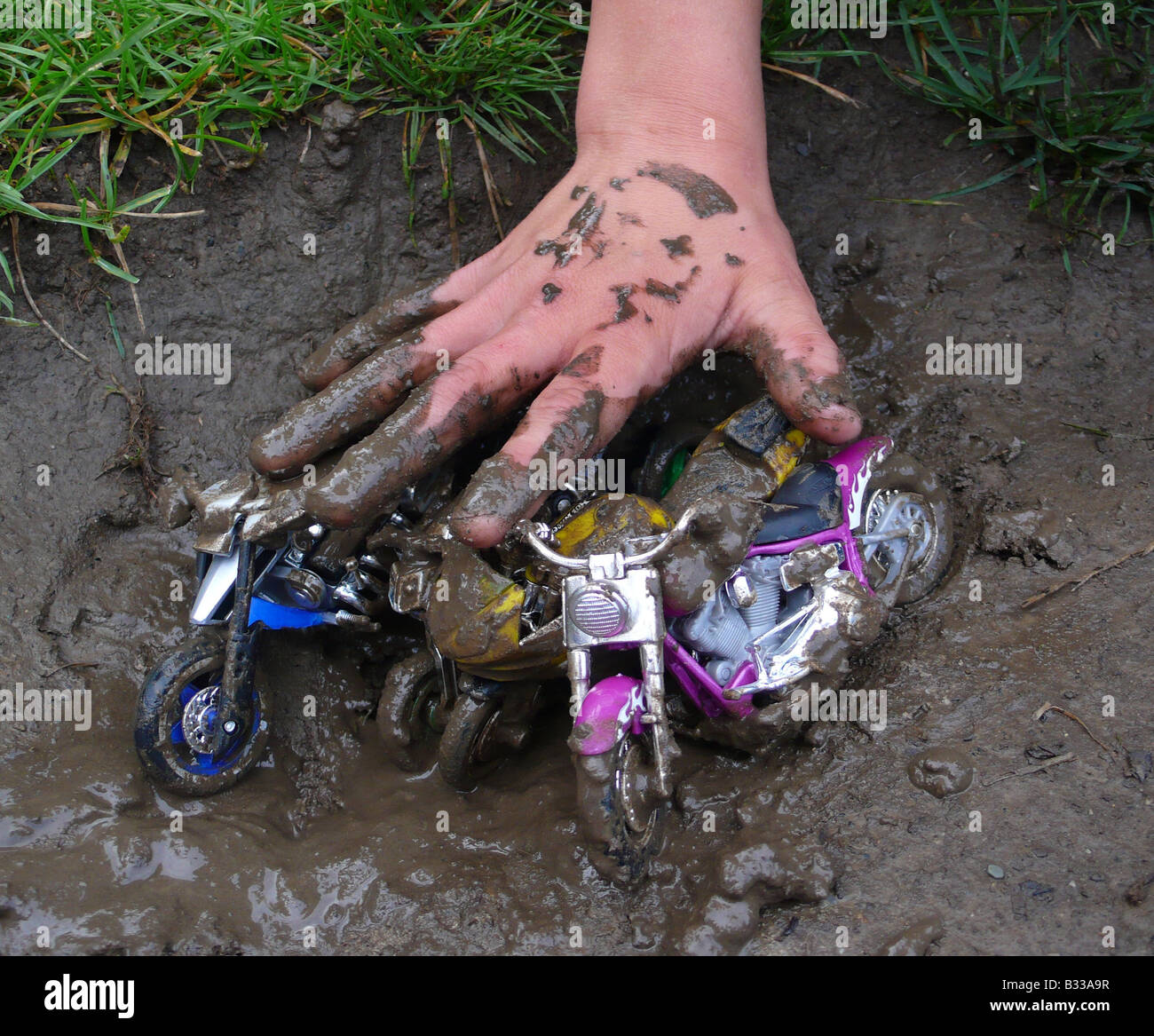 child playing with motor bike toys in mud Stock Photo