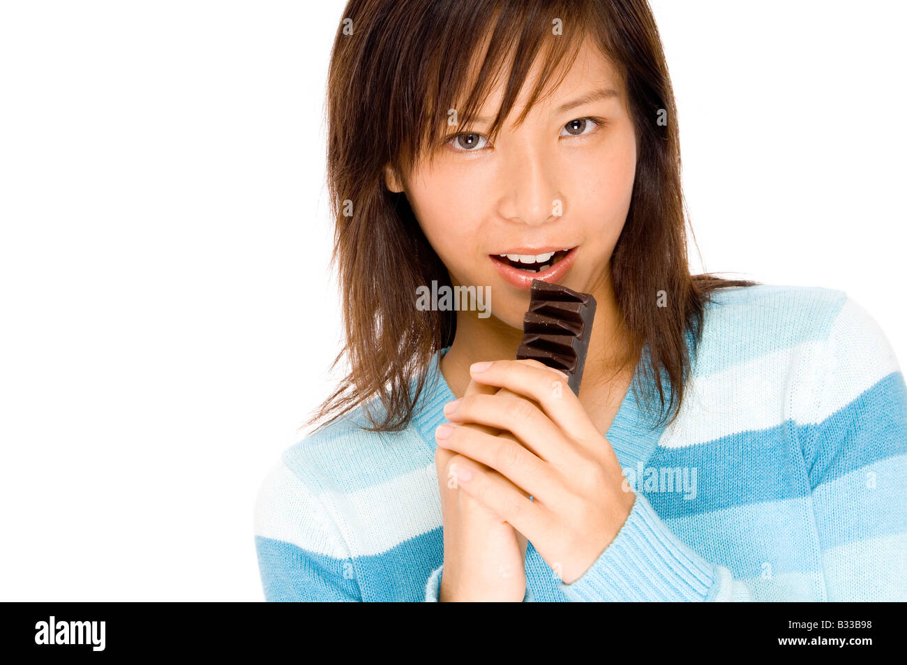 A pretty asian woman gripping a bar of chocolate Stock Photo - Alamy
