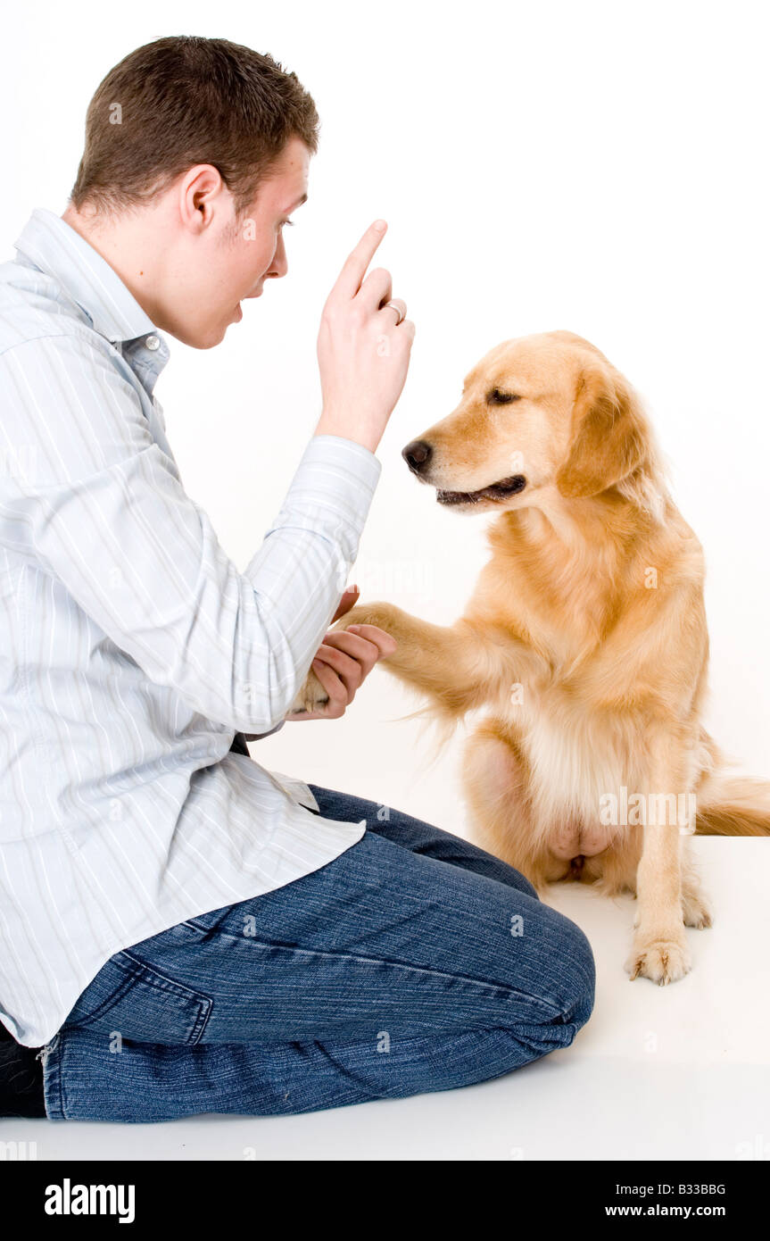 A young man tries to train his pet dog to shake hands/paws Stock Photo