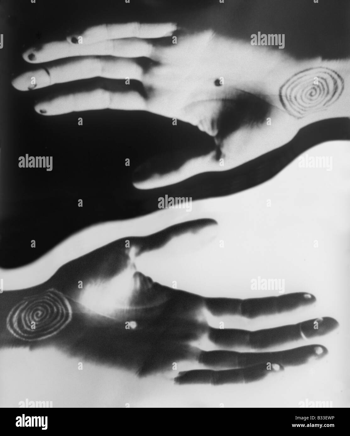 Positive negative hands with spiral and dot tattoos seeming to offer balance by the offset position of one hand over the other Stock Photo