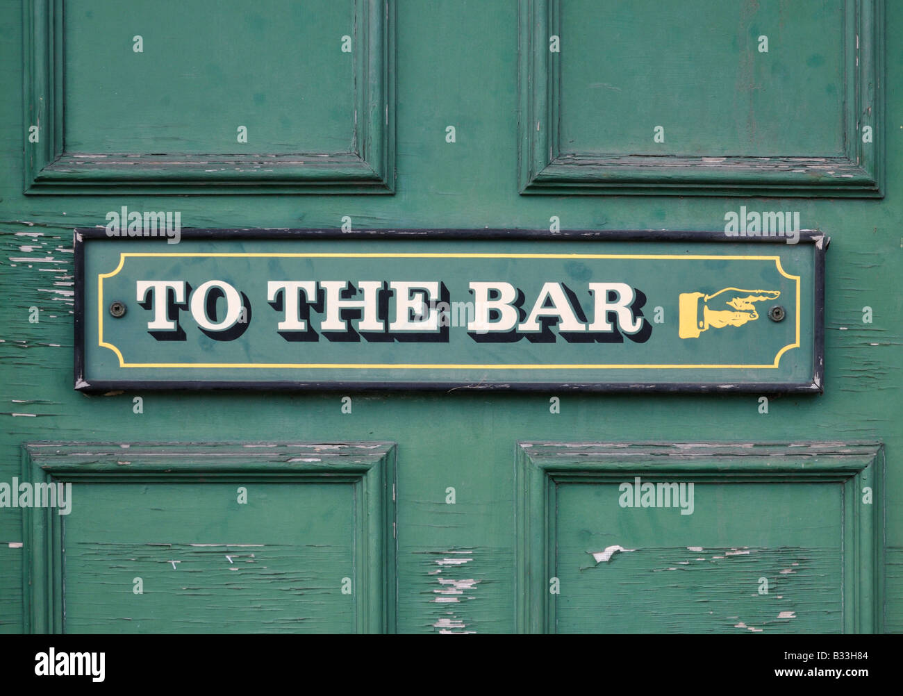Pub door showing weathered sign 'To the bar' with a painted hand pointing to the right 1/2 Stock Photo
