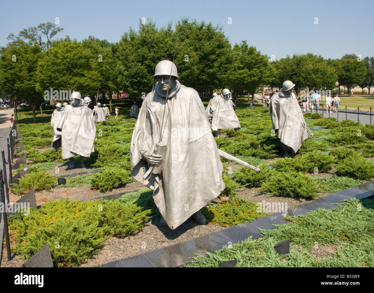 The statues of soldiers in a platoon march warily across a field at the