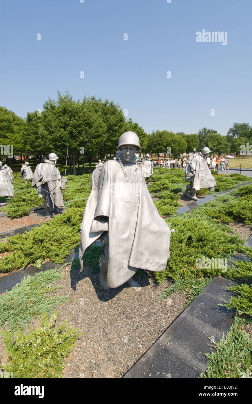 The statues of soldiers in a platoon march warily across a field at the