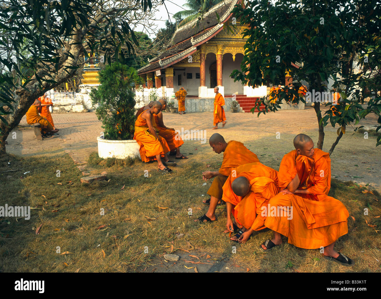Laos Luang Prabang Wat Saen Group of monks resting outside a temple after the morning prayer Stock Photo