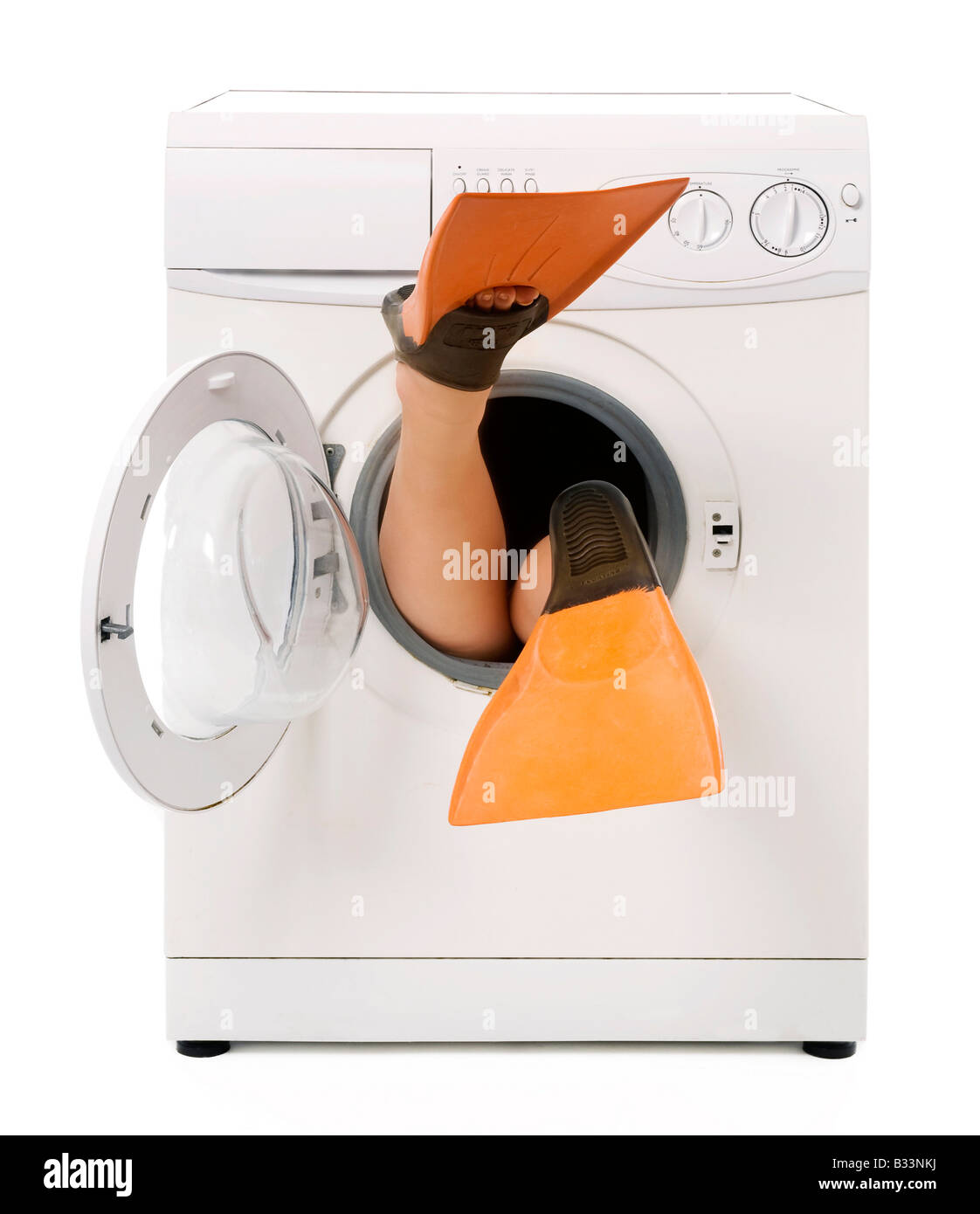 Feet wearing flippers sticking out of a washing machine Stock Photo