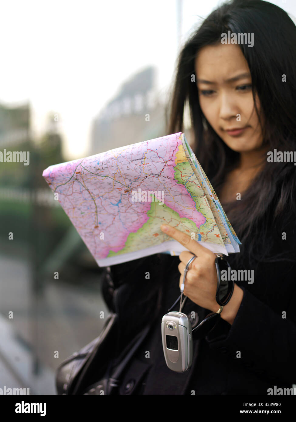 Chinese woman looking at a map to help reorient or locate herself Stock Photo